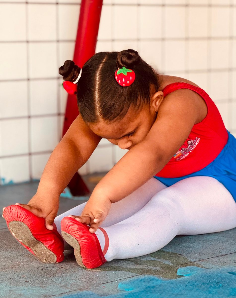 Aluna ajustando a sapatilha vermelha antes da aula de ballet