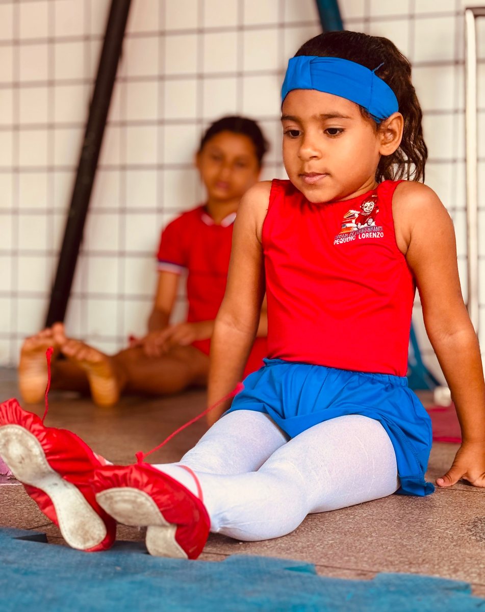 Aluna do Pequeno Lorenzo em aula de ballet, de uniforme vermelho e azul